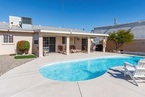 A residential backyard with a swimming pool, patio chairs, and a covered seating area. - Spacious, Super Clean, Ping Pong & Alexa music!! (Lake Havasu)