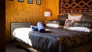 A wooden-paneled room with a bed, pillows, a lamp, and a tapestry. - Howards Hill bed & breakfast (cape schanck)