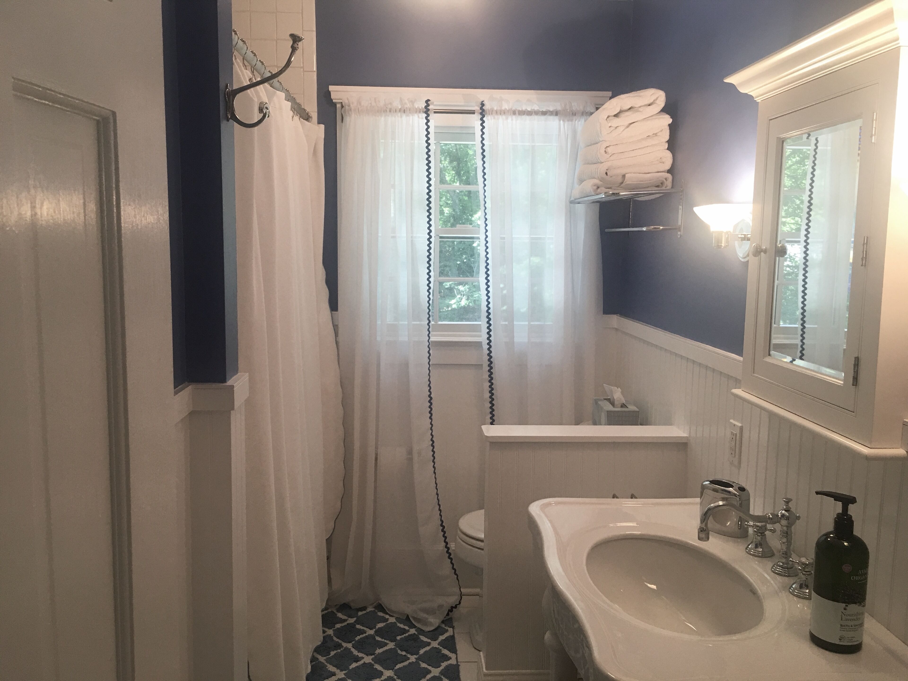 Un baño con lavamanos blanco, un espejo, inodoro y cortina de ducha.