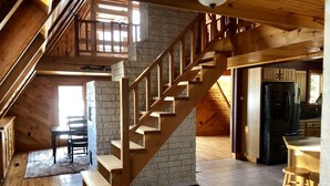 A wooden interior with a staircase, a kitchen, and a dining area. - Great Sacandaga Lakefront Home with 100 feet of deep water access (Hadley)