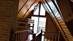 A wooden attic bedroom with a bunk bed, a window, and a wooden railing. - Great Sacandaga Lakefront Home with 100 feet of deep water access (Hadley)
