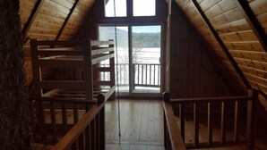 A wooden attic room with a window overlooking a snowy landscape. - Great Sacandaga Lakefront Home with 100 feet of deep water access (Hadley)