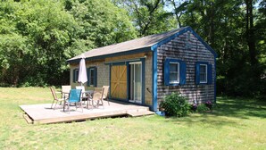 Eine kleine Holzhütte mit einer Terrasse, einem Tisch und Stühlen.