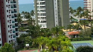 A high-rise building with multiple balconies, a tennis court, and a view of the ocean. - 🌺RIVIERA APARTMENT WITH SEA VIEW (send message before) (Bertioga)