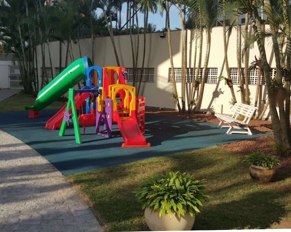 A playground with slides and climbing structures, a bench, and a potted plant. - 🌺RIVIERA APARTMENT WITH SEA VIEW (send message before) (Bertioga)