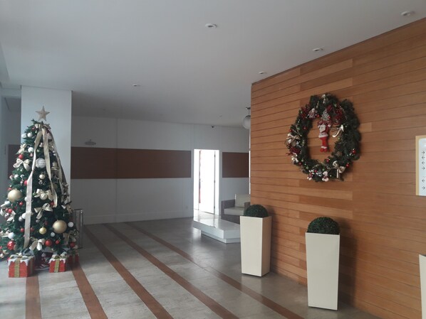 Eine moderne Hotelhalle mit einem Weihnachtsbaum, einer Holzvertäfelung mit einem Kranz und einer Treppe.