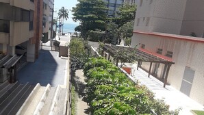 Eine enge Stadtstraße mit Gebäuden an beiden Seiten, einem Fußweg und üppigem Grün.