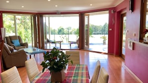 Une salle à manger spacieuse avec une table dressée pour quatre personnes, entourée de chaises. Une grande fenêtre offre une vue sur l’extérieur.