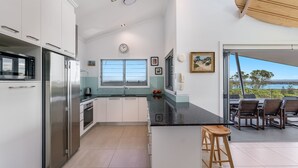 A modern kitchen with stainless steel appliances, a large window, and a view of the outdoors. - Pilotage 4 - Luxury Ocean and River View Penthouse - Holiday Yamba (Yamba)