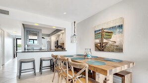 A modern kitchen with a central island, wooden chairs, and a dining table with placemats. - Stunning Ocean View/Sunsets, A true "Gem by the Sea" great for relaxation & fun (Key Largo)