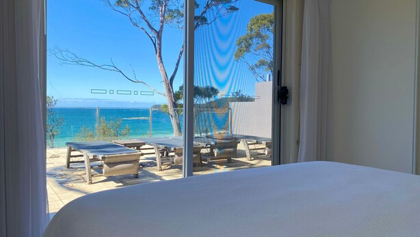 A room with a bed, a view of the sea, and outdoor seating with a table and chairs. - Beachfront Duplex on Denhams (Denhams Beach)