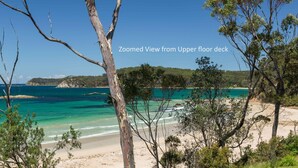 A coastal landscape with clear turquoise waters, sandy beach, and dense greenery. - Beachfront Duplex on Denhams (Denhams Beach)