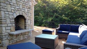 An outdoor patio with stone walls, a fireplace, and wicker furniture. - Private, Luxury Family Retreat 3min  to downtown Ephraim & Sister Bay, Door Co (Sister Bay)