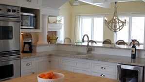 A kitchen with white cabinets, a granite countertop, a built-in microwave, a coffee maker, and a bowl of oranges on the counter. - Private, Luxury Family Retreat 3min  to downtown Ephraim & Sister Bay, Door Co (Sister Bay)