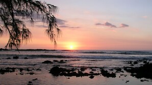 Una playa con rocas y olas al atardecer.