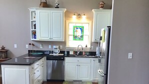 Una cocina con gabinetes blancos, electrodomésticos de acero inoxidable y un ventanal con un diseño de vidrieras.