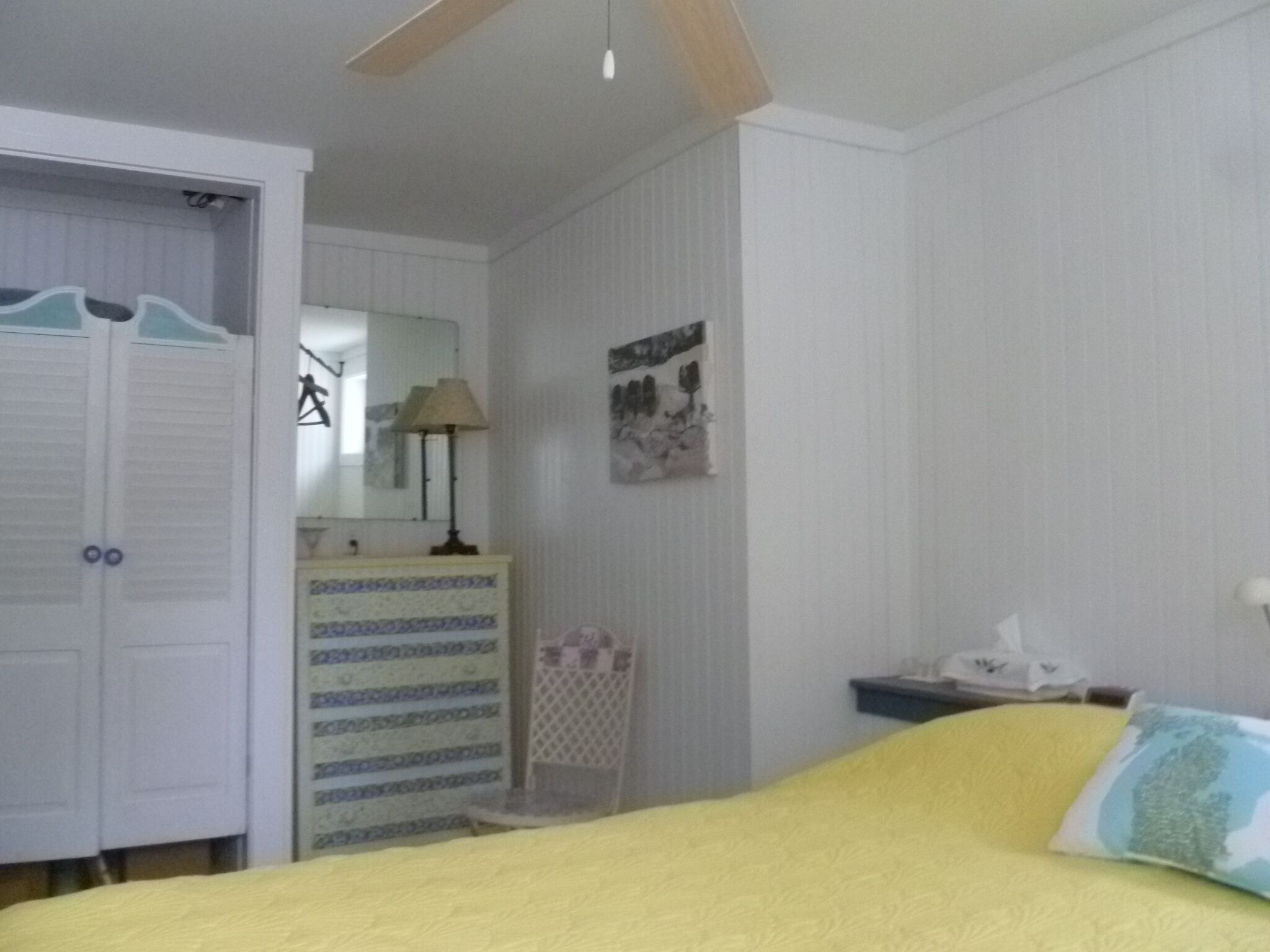 Un dormitorio con cama, armario, cómoda, espejo y un cuadro en la pared.