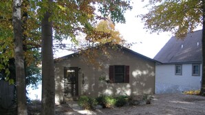 A single-story house with a front door, a small porch, and a gravel driveway.