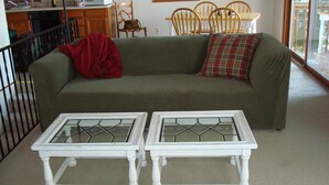 A living room with a green sofa, two white side tables, and a red throw blanket.