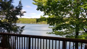 A wooden deck overlooking a calm lake with trees in the background.