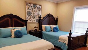 A bedroom with two wooden beds, each with a blue bedspread and matching pillows. There is a nightstand with a lamp between the beds, and a decorative piece on the wall above the nightstand. - TOP LOCATION! Luxury Traditional New Orleans Home, Heart of NOLA (New Orleans)