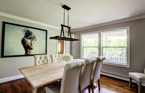Un comedor con una mesa de madera, sillas tapizadas y una lámpara de araña.