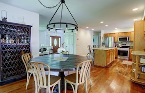 Una cocina con armarios de madera, una isla central y una zona de comedor con una mesa redonda y sillas.