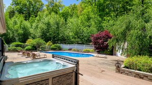 Een achtertuin met een jacuzzi, een zwembad en een houten terras.