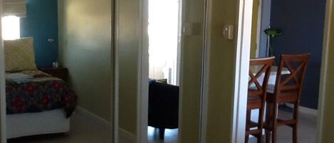 A bedroom with a bed, a nightstand, and a chair. There is a sliding door leading to another room.