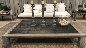 A living room with a dark wooden coffee table, a white sofa with multiple cushions, and a glass bowl with decorative items. - Baan Nub Kluen Condo - Hua Hin (Tambon Nong Kae)