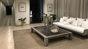 A modern living room with a sofa, a coffee table, and a potted plant. - Baan Nub Kluen Condo - Hua Hin (Tambon Nong Kae)