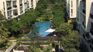 A modern hotel with a central swimming pool surrounded by lush greenery and palm trees. - Baan Nub Kluen Condo - Hua Hin (Tambon Nong Kae)