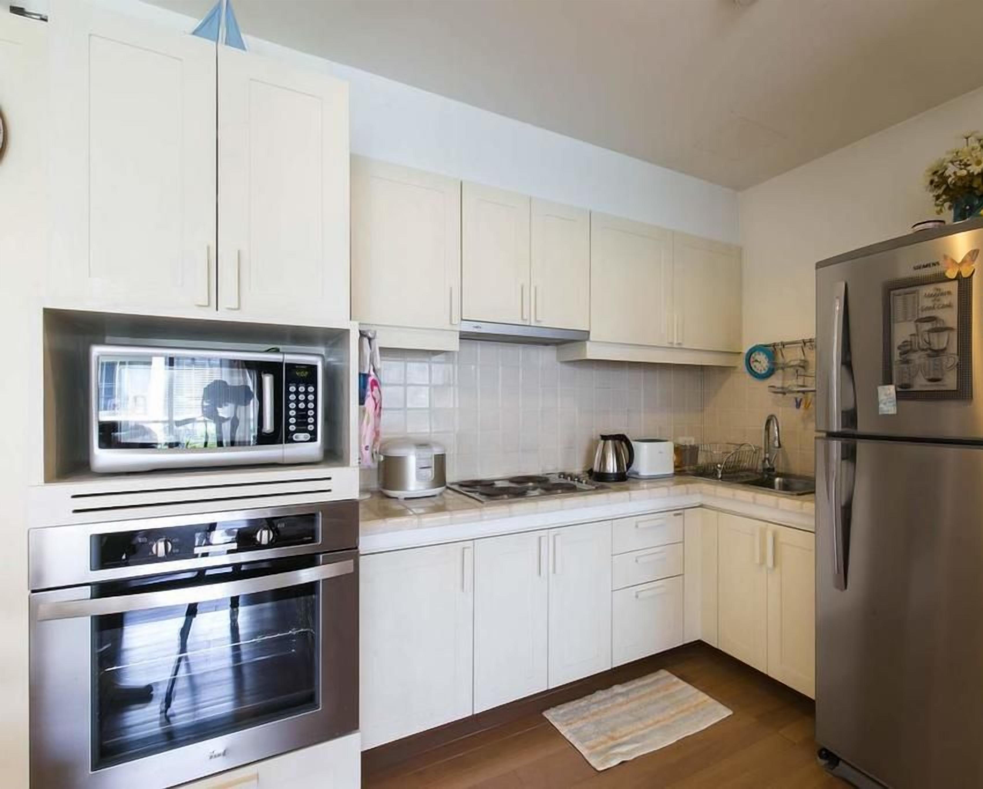 A modern kitchen with white cabinets, stainless steel appliances, and a built-in microwave.