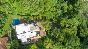 Une vue aérienne d’une maison avec une piscine, entourée d’une végétation luxuriante.