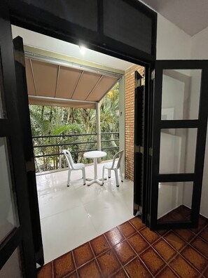 An open doorway leading to a balcony with a table and chairs, a tiled floor, and a view of greenery. - Domingas Dias, 80m from the sea, 4 suites with pool. (Ubatuba)
