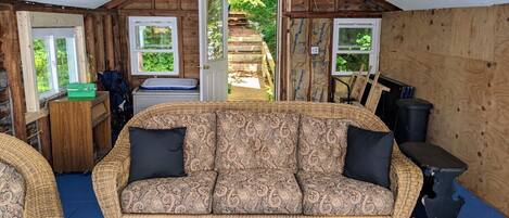 A cozy room with a patterned sofa, a small table, and a view of a garden through an open door.