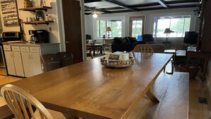 A spacious kitchen with a large wooden table, wooden chairs, and a coffee station. - Picturesque Adirondack Lake Home (Greig)