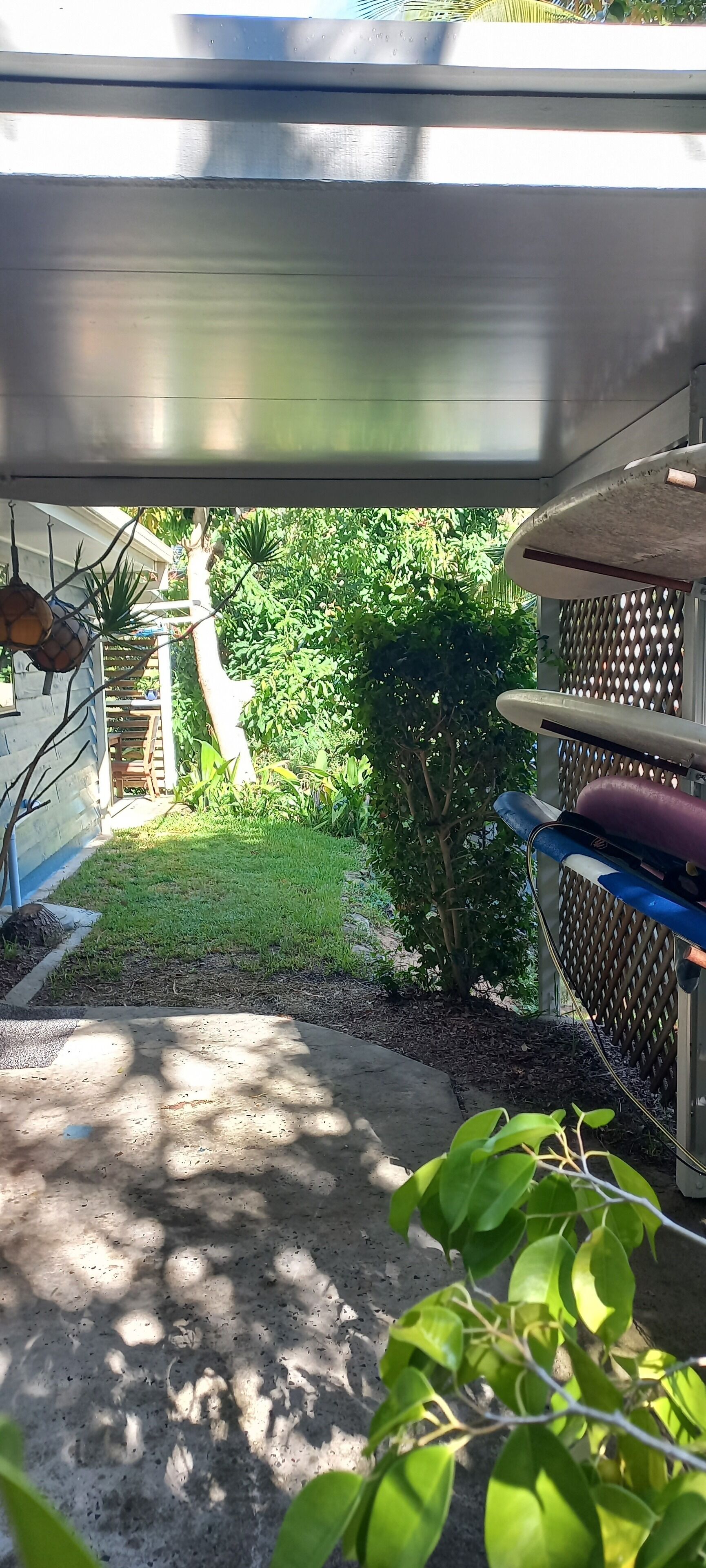 A patio area with a concrete floor, a metal railing, and a view of a green garden with trees and plants.
