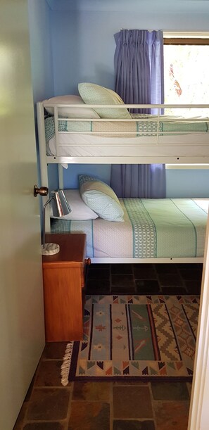 Habitación con literas, un escritorio pequeño, una lámpara y una alfombra estampada.