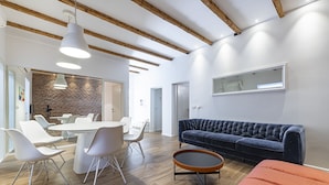 Un intérieur moderne comprenant un coin repas, un canapé bleu foncé et un plafond en bois.