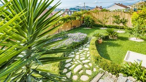 Un jardin avec un chemin de pierres, une clôture en bois et une variété de plantes.