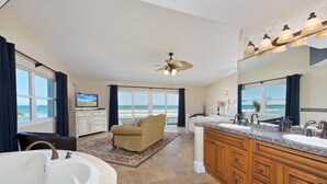 A spacious bathroom with a large bathtub, a vanity with two sinks, and a ceiling fan.