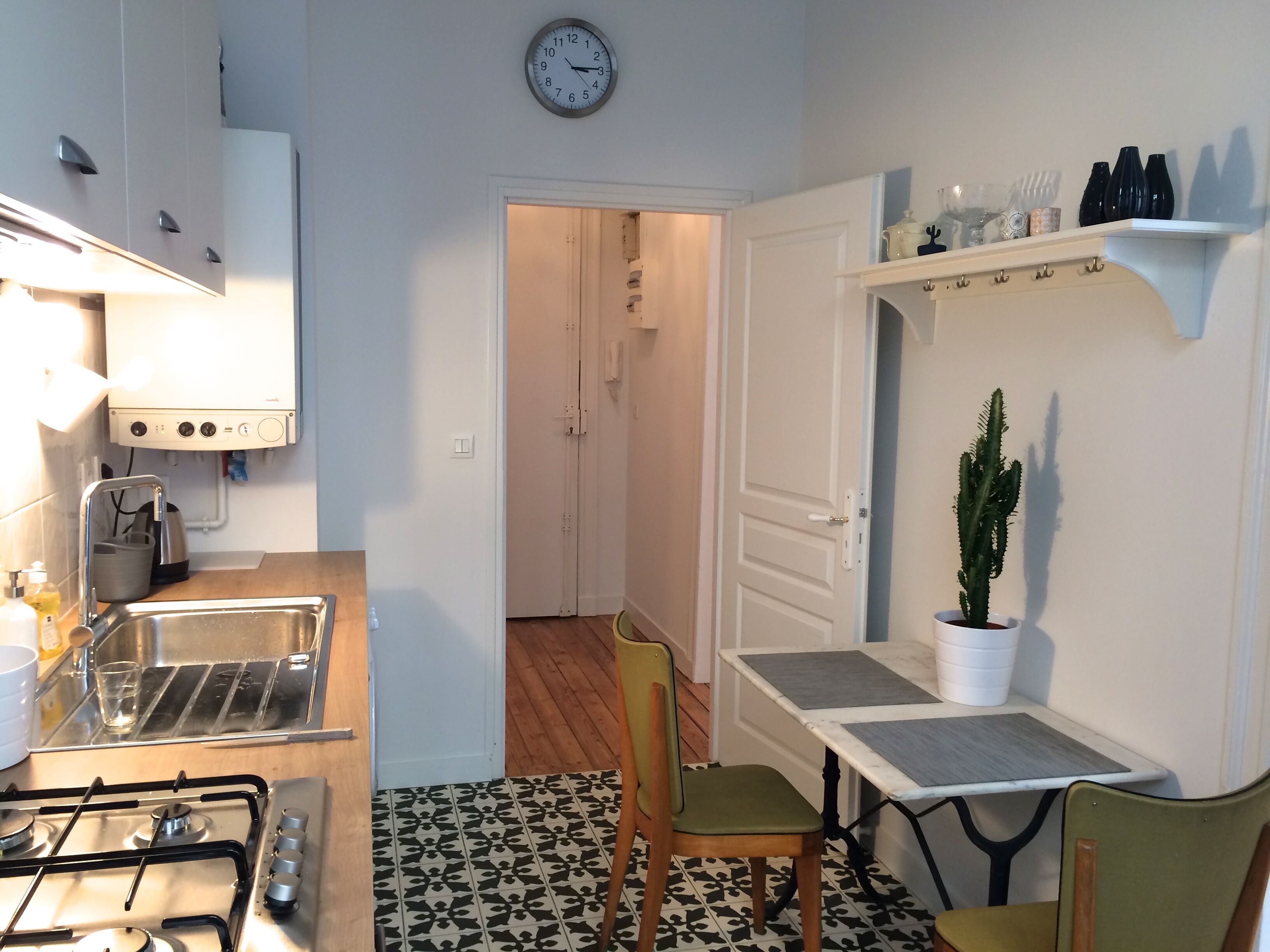 Une petite cuisine équipée d’une cuisinière à gaz, d’un évier et d’une horloge murale.