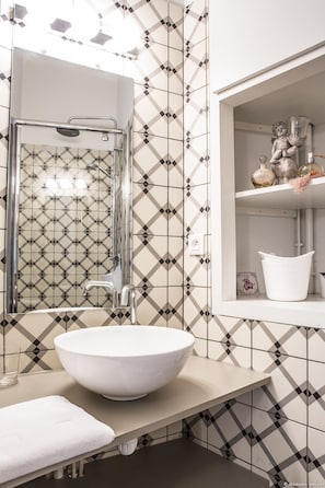 A bathroom with a large vessel sink, a glass shower enclosure, and a shelf with decorative items. - Appartement chic et raffiné dans l'un des meilleurs quartiers de Bordeaux. (Bordeaux)