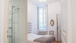 Une chambre à coucher avec un lit, un radiateur, une fenêtre et une porte.