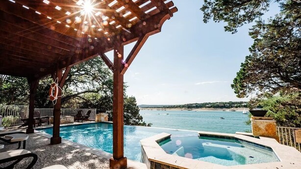 A pool area with a hot tub, lounge chairs, and a pergola with a rope swing.