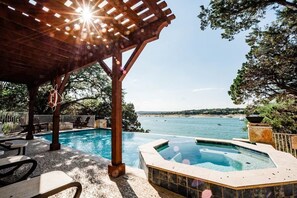 A pool area with a hot tub, lounge chairs, and a pergola with a rope swing.
