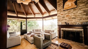 A spacious living room with a fireplace, a ceiling fan, and a stone wall with a sculpture.