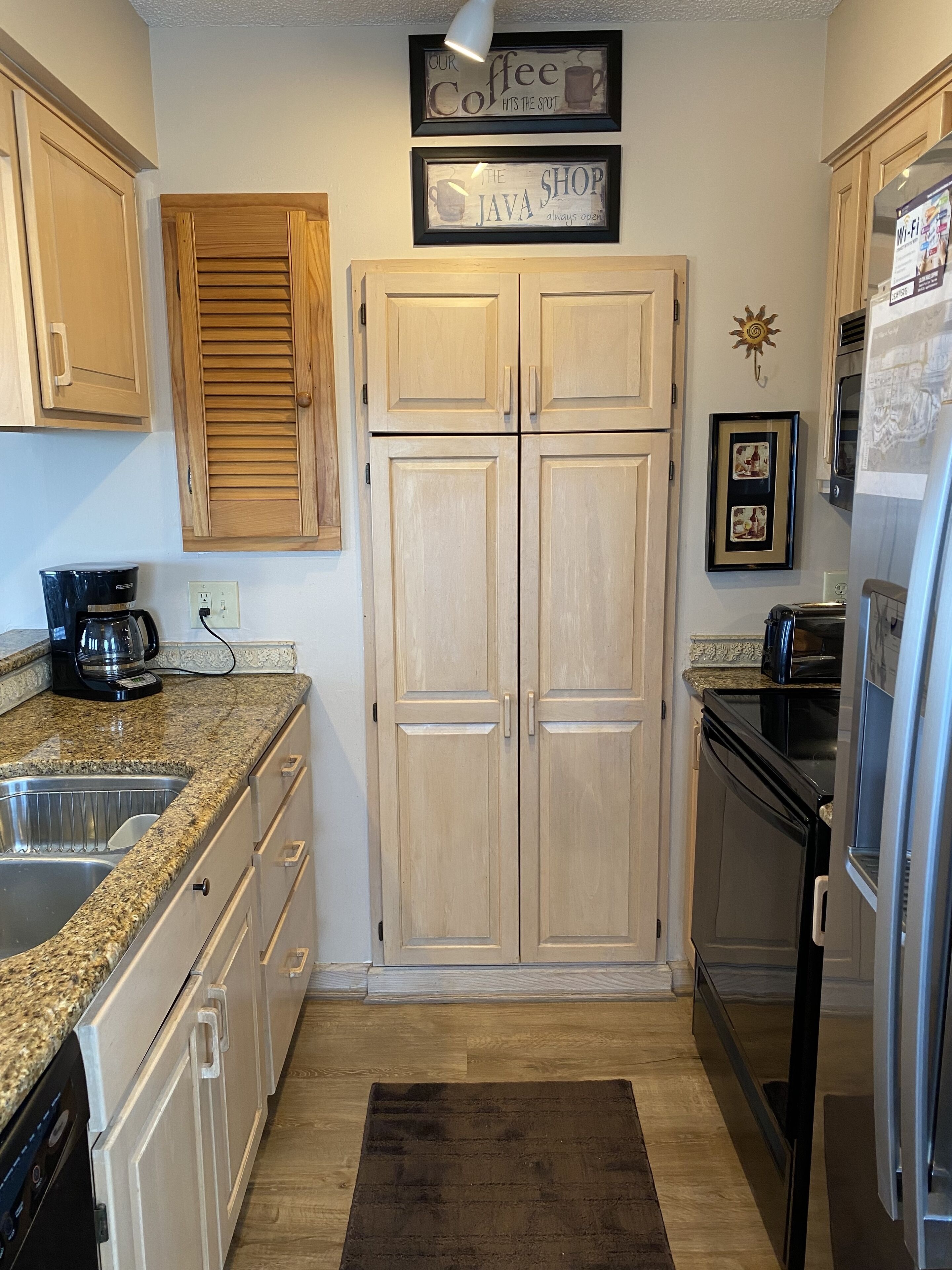 A kitchen with wooden cabinets, a coffee maker, a toaster, and a refrigerator.