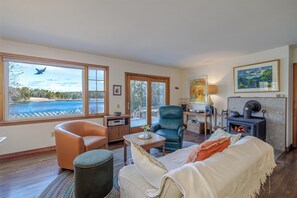 Una sala de estar acogedora con chimenea, un sofá cómodo, una mesa de comedor y vistas a un lago.